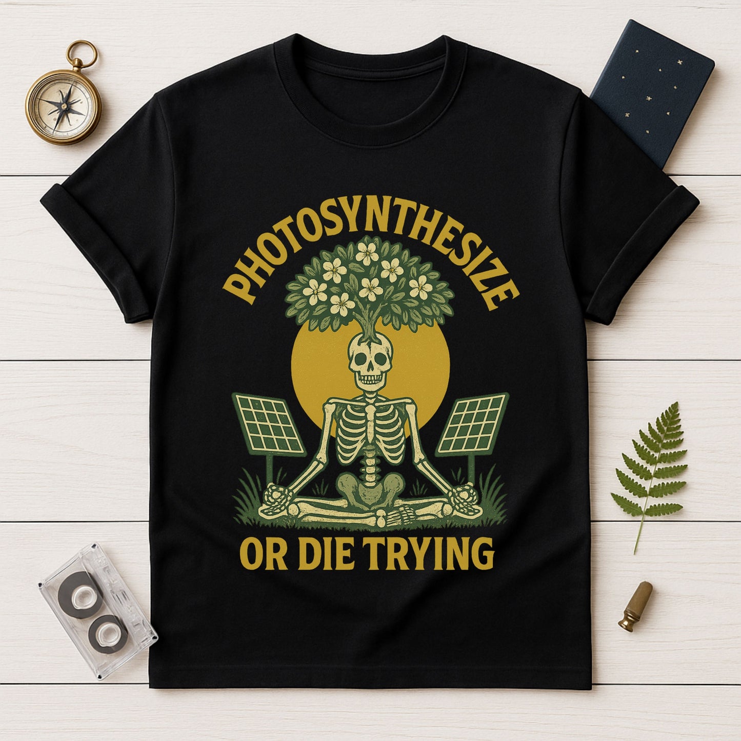 Black t-shirt with skeleton and plant design on a wooden surface with decorative items.