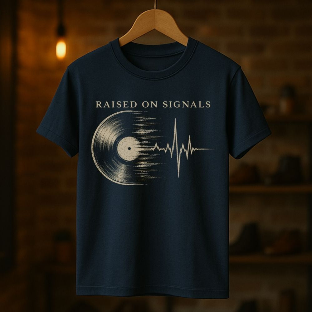Navy blue t-shirt with 'Raised on Signals' design on a wooden hanger against a dark background