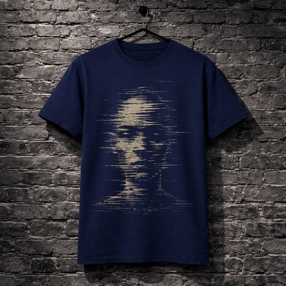 A navy blue short-sleeve t-shirt hanging on a black hanger against a dark gray brick wall. The front of the shirt features a distressed, pixelated graphic of a face in a light beige or cream color.