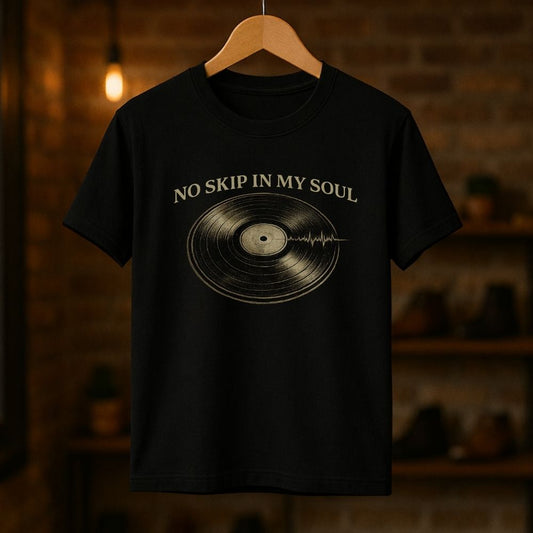Black t-shirt with vinyl record design and 'No Skip in My Soul' text on a wooden hanger against a brick wall.