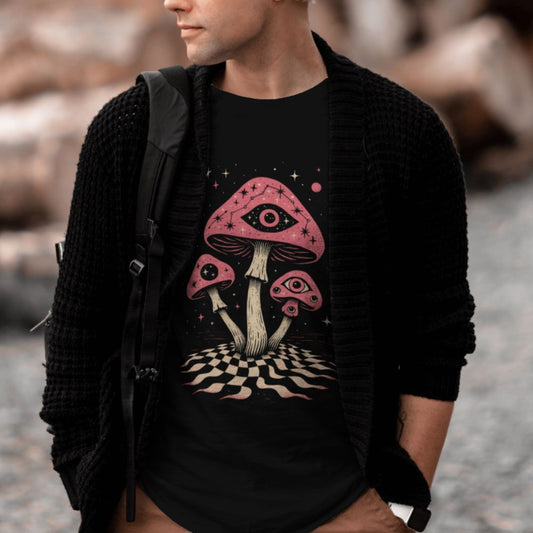Male model wearing black surreal mushroom eye graphic T-shirt styled in outdoor lifestyle setting