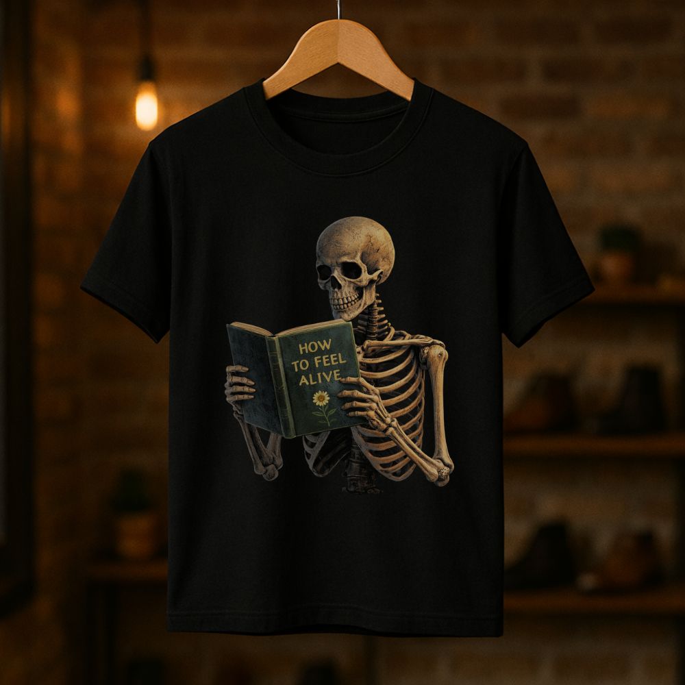 Black unisex graphic T-shirt hanging on a wooden hanger showing a skeleton reading "How to Feel Alive"