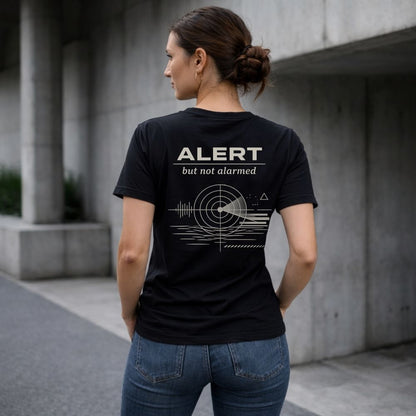 Person wearing a black t-shirt with 'Alert but not alarmed' design outdoors.