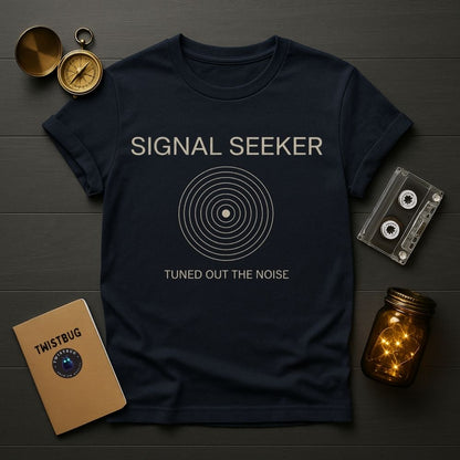 Navy blue t-shirt with 'Signal Seeker' design on a wooden surface with vintage items.