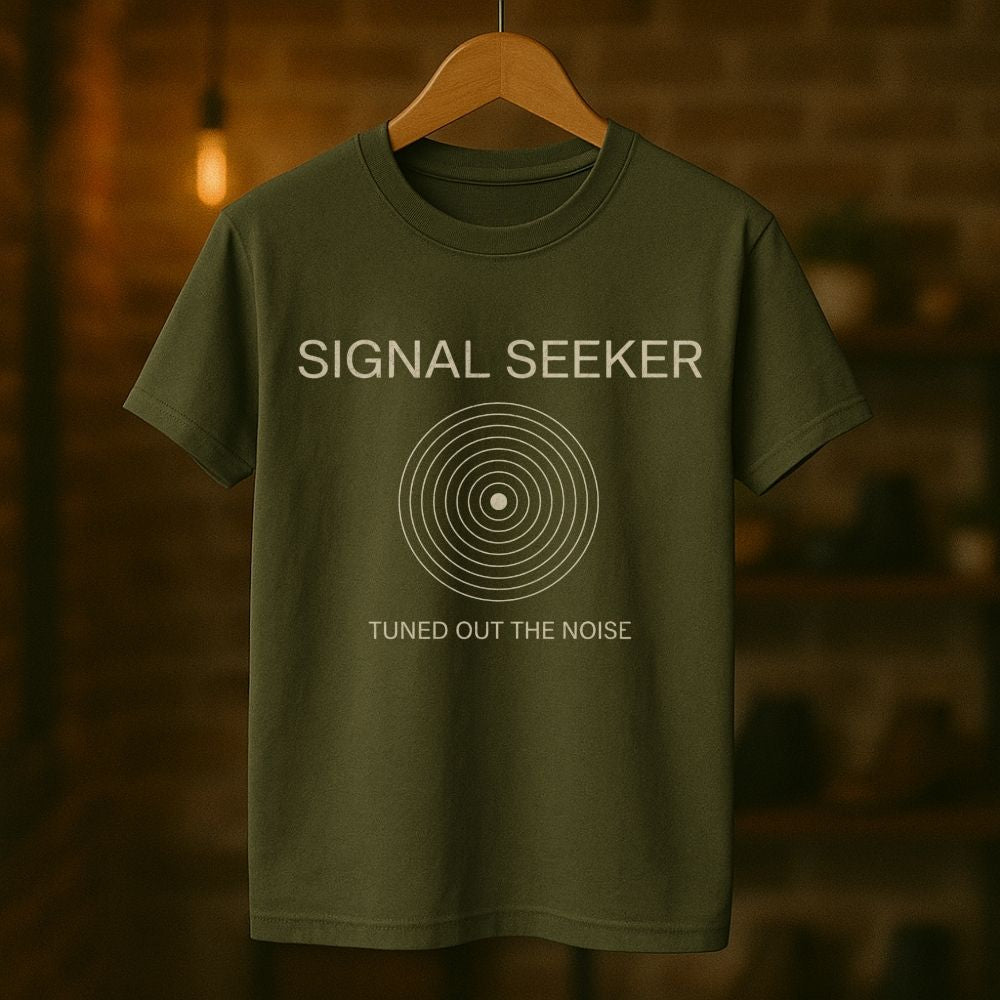Green t-shirt with 'Signal Seeker' text on a hanger against a blurred background