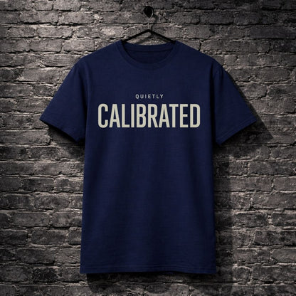 Navy blue t-shirt with 'CALIBRATED' text on a brick wall background
