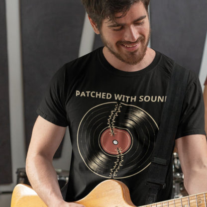 Man wearing a black t-shirt with a vinyl record design and text, holding a guitar.