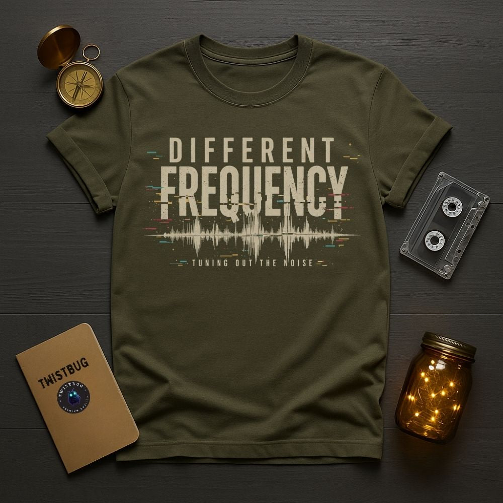 Green t-shirt with 'Different Frequency' design on a wooden surface with vintage items.