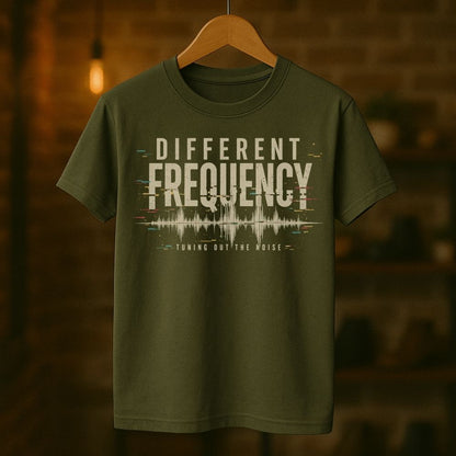 Green t-shirt with 'Different Frequency' text on a wooden hanger against a blurred background