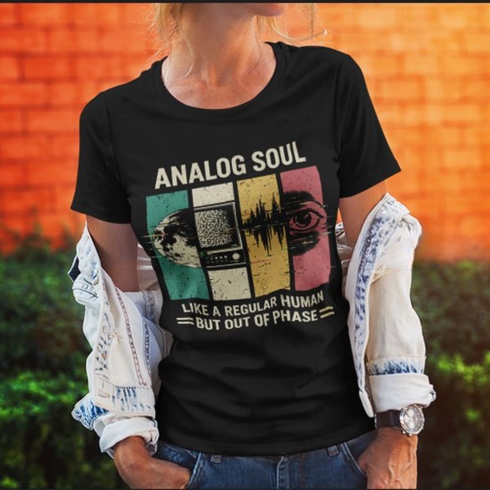 Person wearing a black t-shirt with 'Analog Soul' design against an orange wall.
