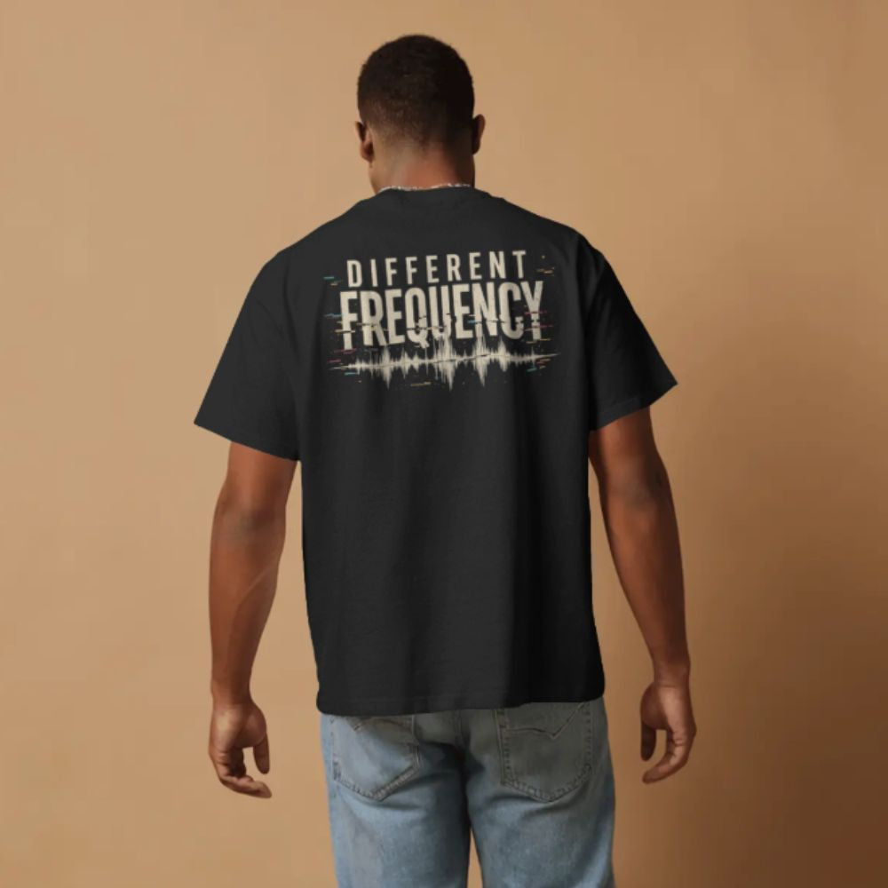 Person wearing a black t-shirt with 'Different Frequency' text on the back against a beige background