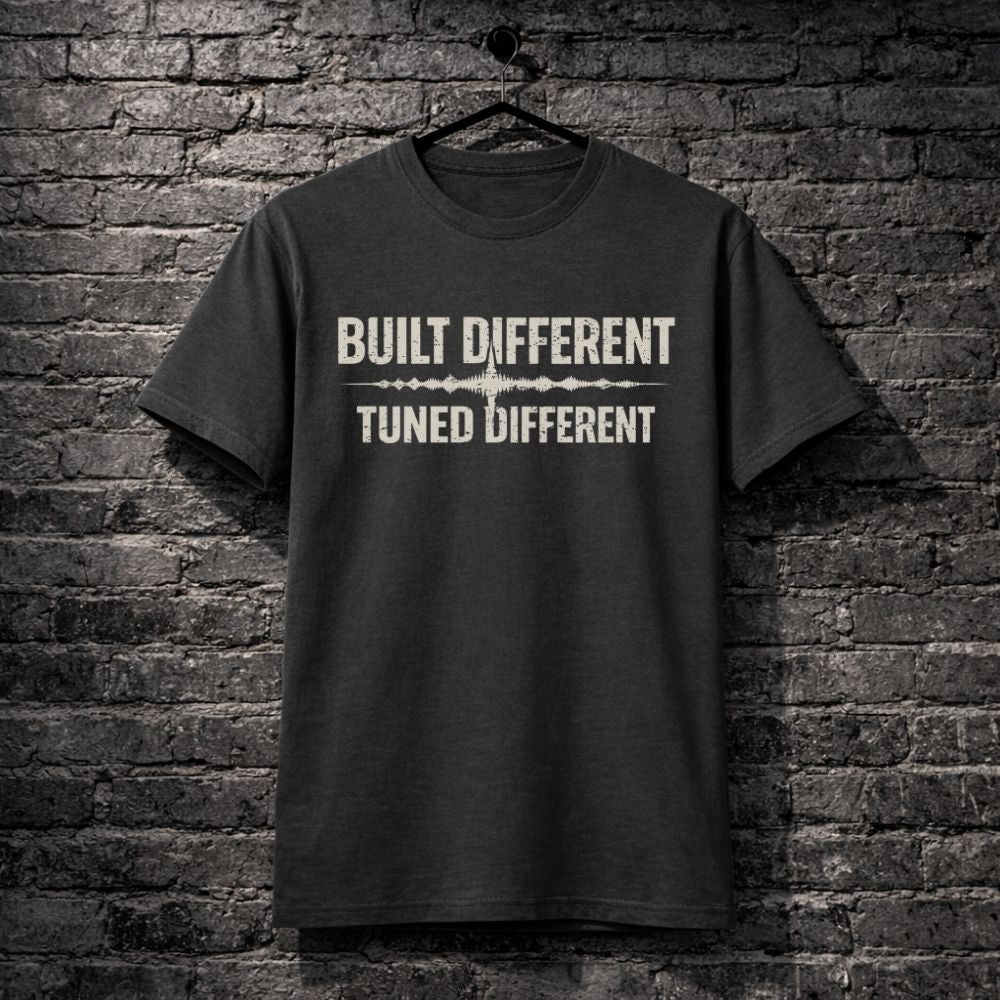 Black t-shirt with 'Built Different Tuned Different' text on a brick wall background