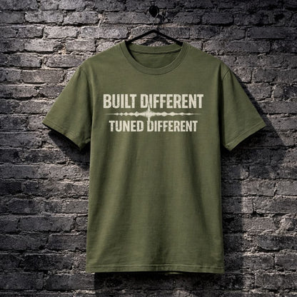 Green t-shirt with text 'Built Different Tuned Different' on a brick wall background