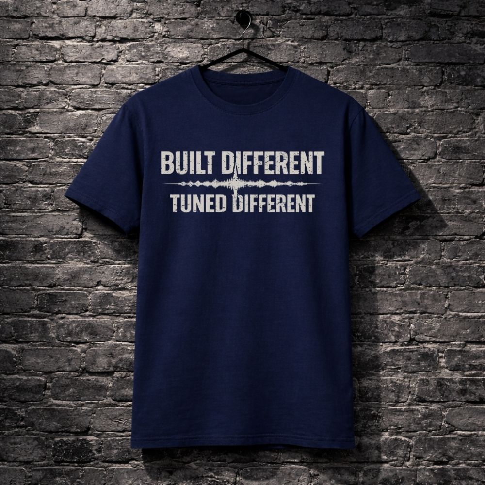 Navy blue t-shirt with 'Built Different Tuned Different' text on a brick wall background