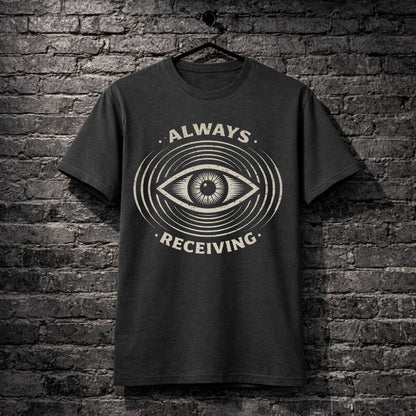 Black t-shirt with eye design and 'Always Receiving' text on a brick wall background