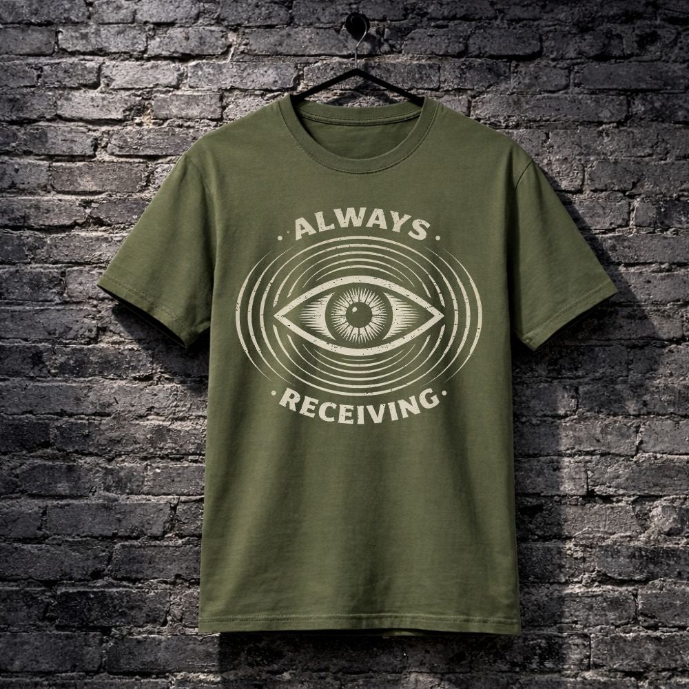 Green t-shirt with eye design and text 'Always Receiving' on a brick wall background