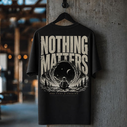 Black t-shirt with 'Nothing Matters' graphic design hanging on a wooden hanger against a concrete wall.