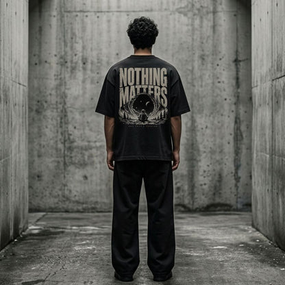 Person wearing a black t-shirt with 'NOTHING MATTERS' text in a concrete setting