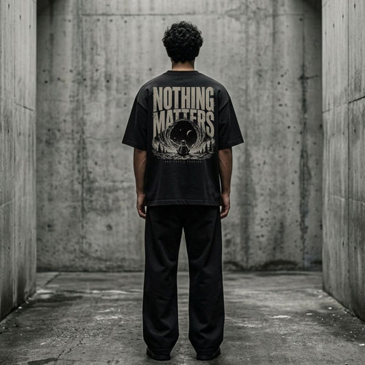 Person wearing a black t-shirt with 'NOTHING MATTERS' text in a concrete setting