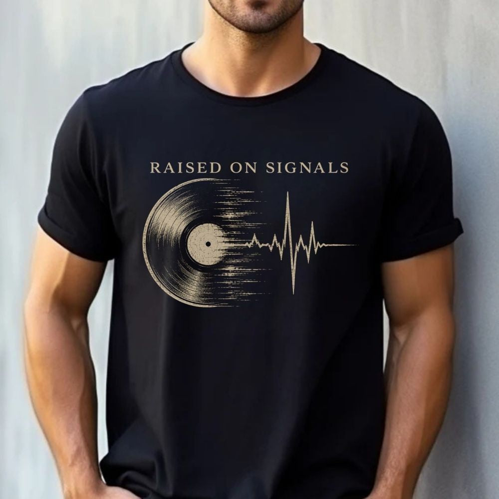 Person wearing a black t-shirt with 'Raised on Signals' design against a light gray background
