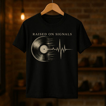 Black t-shirt with 'Raised on Signals' design on a wooden hanger against a dark background