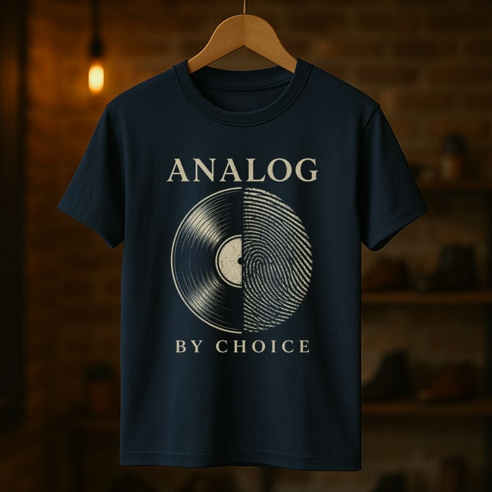 Navy blue t-shirt with vinyl record design and 'Analog by Choice' text on a wooden hanger against a dark background.