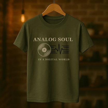Green t-shirt with 'Analog Soul in a Digital World' text and graphic on a wooden hanger against a blurred background.