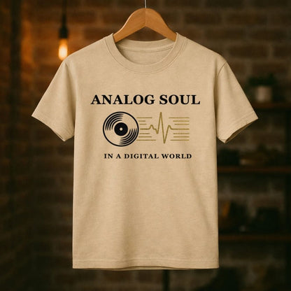 Beige t-shirt with 'Analog Soul in a Digital World' text and graphic on a wooden hanger against a blurred background.