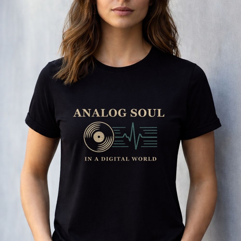Black unisex graphic t-shirt with "Analog Soul in a Digital World" typography and retro vinyl heartbeat graphic, worn by a female model