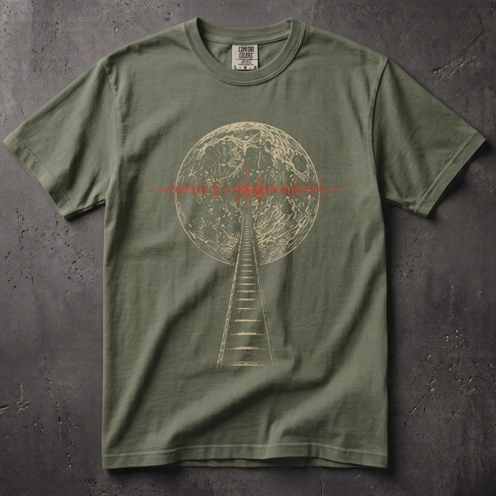An olive green crewneck t-shirt featuring a graphic print of a radio tower reaching toward a moon-like sphere with a red signal wave across the center. The shirt is laid flat on a dark, textured concrete surface.