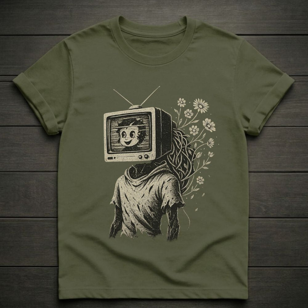 Green t-shirt with a graphic design of a person with a TV head and flowers on a wooden surface