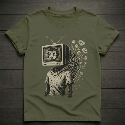 Green t-shirt with a graphic design of a person with a TV head and flowers on a wooden surface