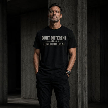 Man wearing a black t-shirt with 'Built Different Tuned Different' text in a dark setting.