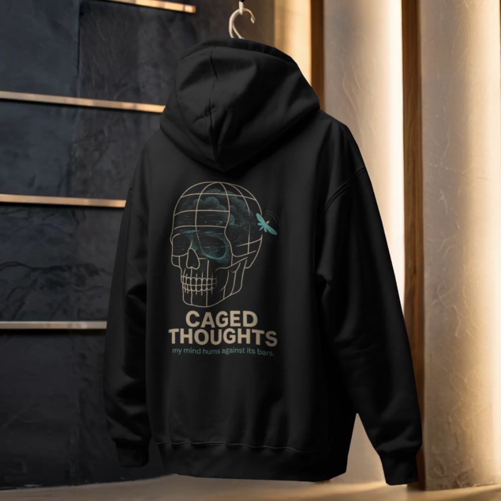 Black Caged Thoughts hoodie hanging on display, showing skull cage back graphic and text design