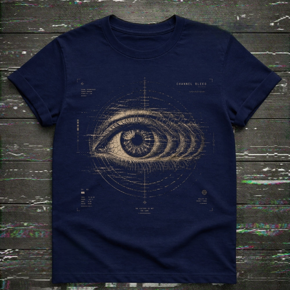 A navy blue short-sleeve t-shirt with a detailed beige blueprint-style eye graphic on the front, laid flat on a dark rustic wooden background.