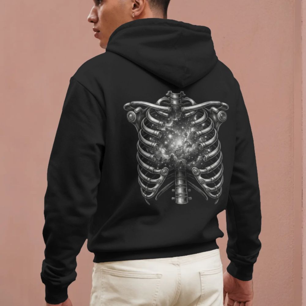 Model wearing a black hoodie featuring a surreal ribcage opening into a star-filled galaxy on the back.