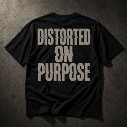 A black short-sleeve t-shirt laid flat on a dark textured concrete surface, featuring the phrase 'DISTORTED ON PURPOSE' printed in a large, distressed light gray font on the back.