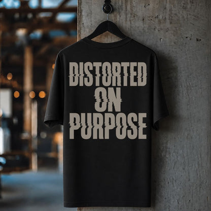 A black short-sleeve t-shirt hanging on a black hanger against a textured concrete pillar, featuring a large distressed beige graphic print that reads 'DISTORTED ON PURPOSE'.