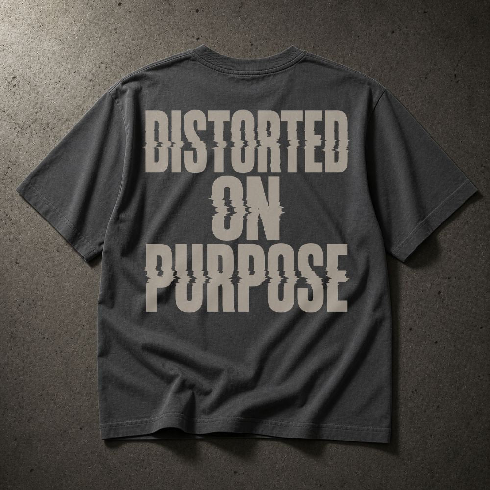 A dark gray t-shirt with a large distressed off-white text graphic reading 'DISTORTED ON PURPOSE' on the back, laid flat on a textured gray surface.