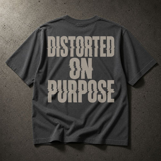 A dark gray t-shirt with a large distressed off-white text graphic reading 'DISTORTED ON PURPOSE' on the back, laid flat on a textured gray surface.