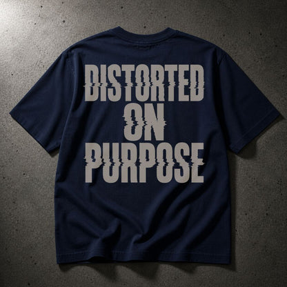 A navy blue short-sleeve t-shirt with the phrase 'DISTORTED ON PURPOSE' printed in a large, distressed light gray font across the back, laid flat on a dark textured concrete surface.