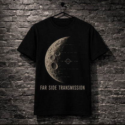 A black short-sleeve t-shirt hanging on a black hanger against a dark gray brick wall. The shirt features a beige graphic of a detailed moon with crater rings and a targeting crosshair, with the text 'FAR SIDE TRANSMISSION' printed below in beige.