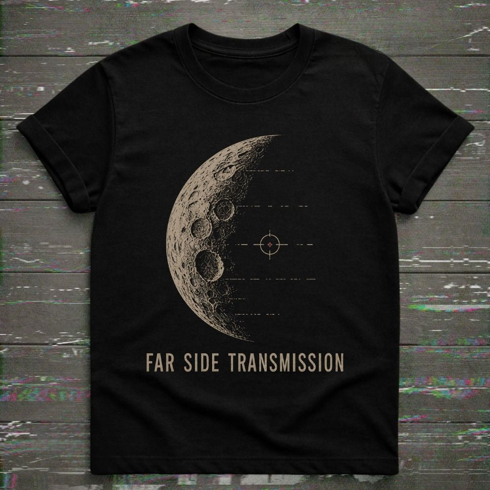 A black short-sleeve crewneck t-shirt featuring a distressed beige graphic of the moon's far side with a target symbol and the text 'FAR SIDE TRANSMISSION' printed below, displayed flat on a dark wood plank background.