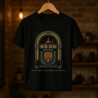 A black short-sleeve t-shirt hanging on a wooden hanger against a warm, blurred brick wall background. The shirt features a vintage-style jukebox graphic in teal, gold, and brown, with the text 'GOOD TIMES.