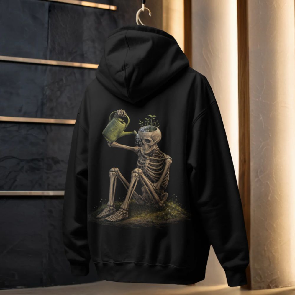 Black hoodie hanging in a studio with surreal skeleton watering plants growing from its head, inner signal artwork