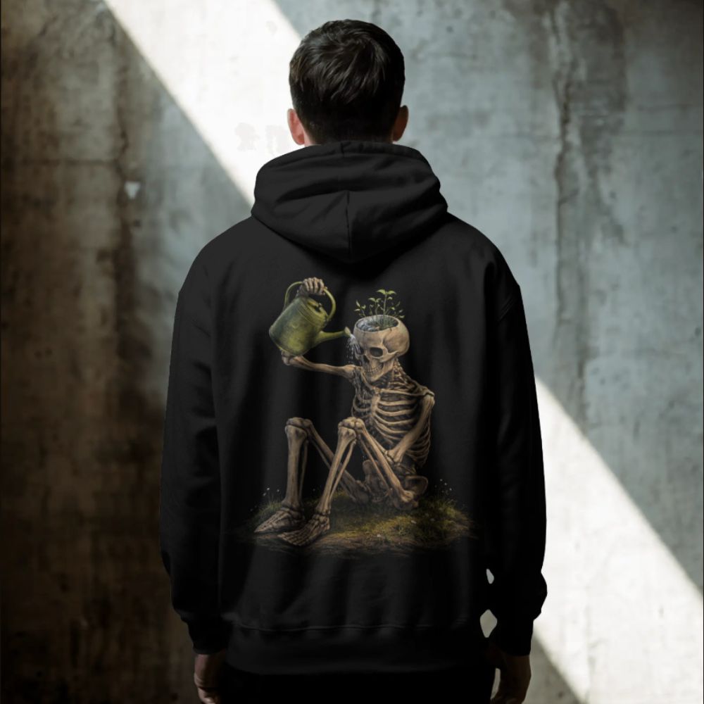 Person wearing a black hoodie with surreal skeleton watering plants from its skull, emotional surreal streetwear design