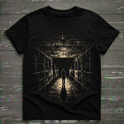 A black short-sleeve t-shirt with a distressed beige graphic print of a figure walking down a dark, empty hallway, laid flat on a dark wood plank background.
