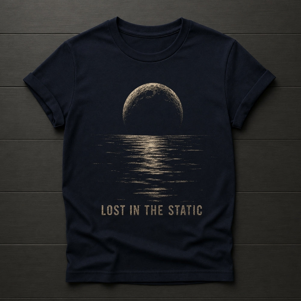 A dark navy blue t-shirt laid flat on a dark wood plank background. The shirt features a graphic print of a half-moon reflecting light on water, with the text 'LOST IN THE STATIC' printed below in a distressed beige font.