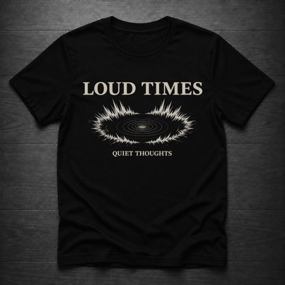 A black short-sleeve t-shirt laid flat on a dark wood background, featuring a cream-colored graphic with the text 'LOUD TIMES' and 'QUIET THOUGHTS' surrounding a soundwave design.