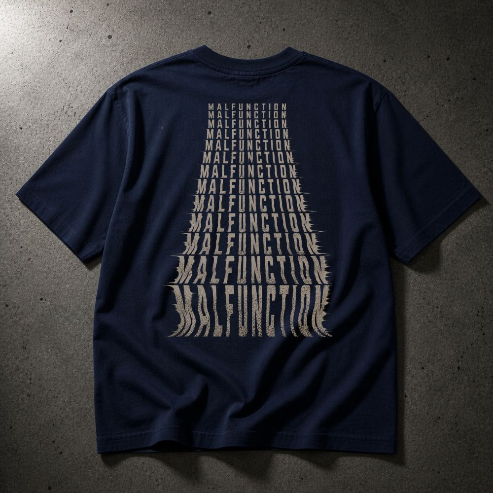 A navy blue short-sleeve t-shirt laid flat on a textured gray concrete surface, featuring a large graphic print on the back in a light beige color that spells out 'MALFUNCTION' in a tapered, layered font.